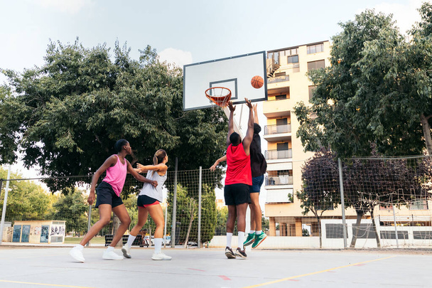 Interraciale groep spelen van een spel basketbal in de stad rechter op een zonnige zomerdag - Foto, afbeelding
