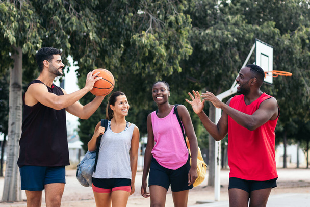 Grupa przyjaciół w odzieży sportowej będzie grać w koszykówkę na boisku - Zdjęcie, obraz