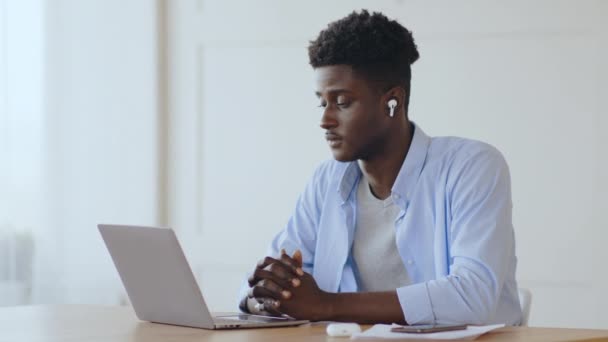 Τηλεδιάσκεψη. Νεαρός Αφρικανός υπάλληλος που συνομιλεί με συναδέλφους μέσω video chat σε laptop, που εργάζεται από το σπίτι - Πλάνα, βίντεο