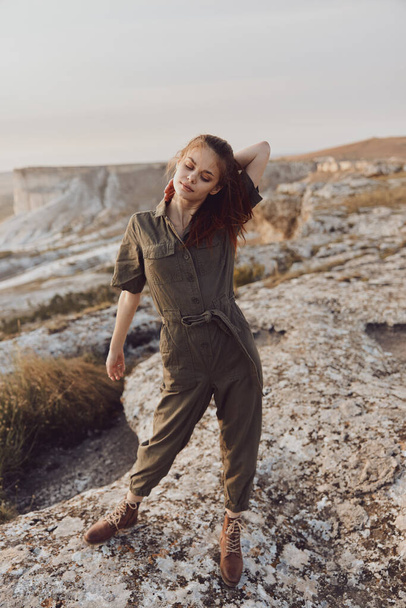 Solitaria giovane donna in tuta verde oliva in piedi sulla cima del deserto rock nel concetto di avventura di viaggio - Foto, immagini
