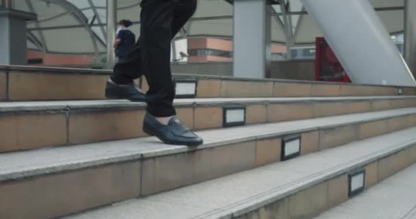 Gambe uomo primo piano in pantaloni da lavoro e scarpe che scendono i gradini del centro città. Piedi impiegato con fiducia dimettersi passi concreti. Piedi in scarpe alla moda salgono rapidamente un passo dopo l'altro - Filmati, video