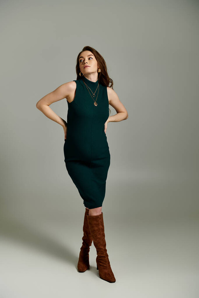 Eine stilvolle, schwangere Frau posiert anmutig in einem leuchtend grünen Kleid, das Eleganz und Selbstbewusstsein ausstrahlt. - Foto, Bild