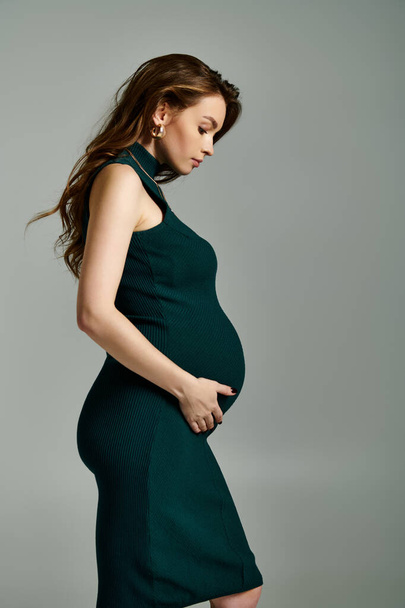 Een stralende zwangere vrouw in een elegante groene jurk straalt vreugde en anticipatie. - Foto, afbeelding