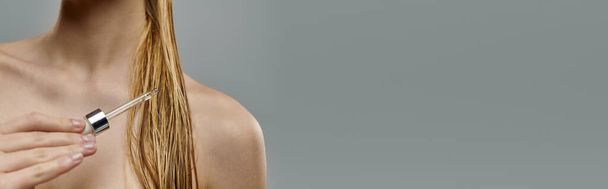 Femme séduisante tenant un sérum capillaire, affichant sa routine de soins capillaires avec des cheveux mouillés. - Photo, image