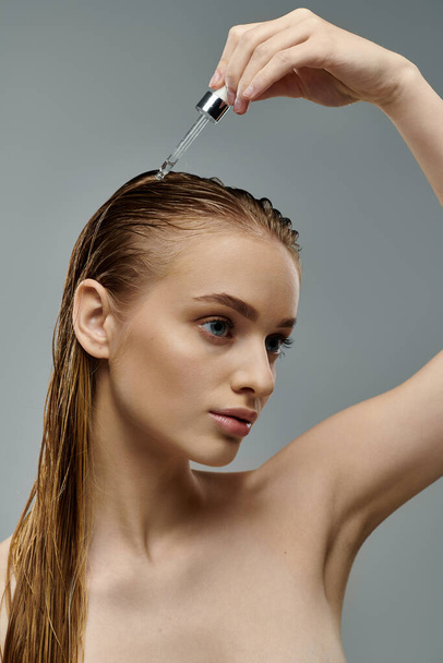 Mulher bonita segurando um soro de cabelo, exibindo sua rotina de cuidados com o cabelo com o cabelo molhado. - Foto, Imagem