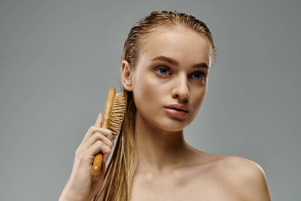 A beautiful young woman demonstrating her hair care routine with a brush in hand. - Fotoğraf, Görsel