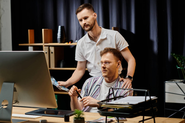 Günlük kıyafetli iki adam ofis ortamında bir bilgisayarın üzerinde birlikte çalışıyorlar.. - Fotoğraf, Görsel