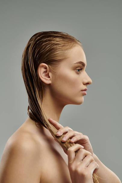 Mujer joven con cabello largo aplicando tiernamente productos para el cuidado del cabello. - Foto, Imagen