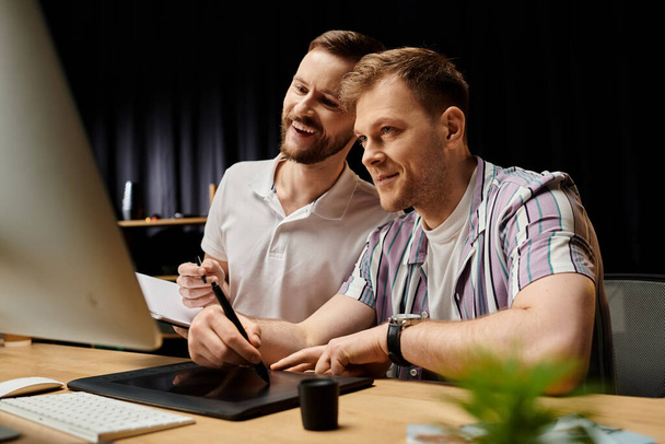 Két férfi alkalmi ruhában, boldogan dolgoznak együtt egy projekten egy laptop segítségével egy íróasztalnál.. - Fotó, kép