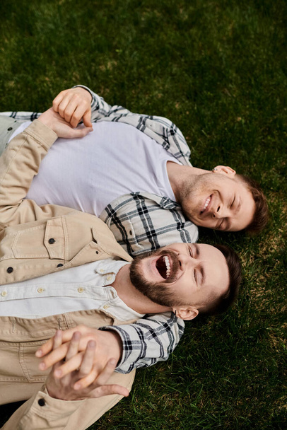 Due uomini in abbigliamento confortevole sdraiati su un lussureggiante campo verde. - Foto, immagini