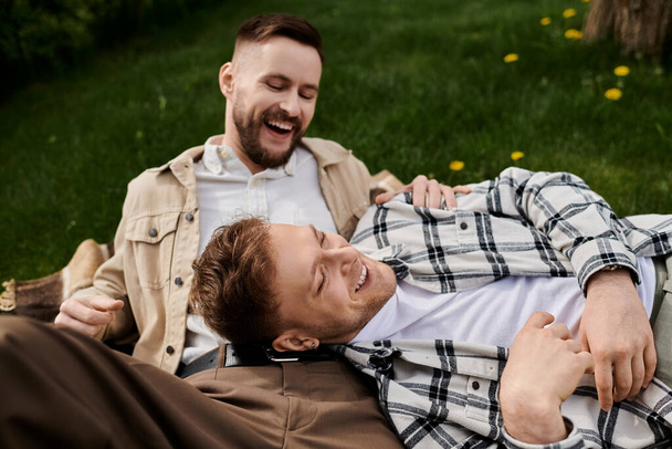 Δύο άνδρες σε casual ενδυμασία χαλαρώνοντας σε χορταριασμένο πεδίο. - Φωτογραφία, εικόνα