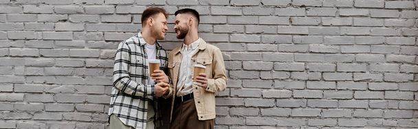 Twee mannen in casual kleding staan bij een bakstenen muur. - Foto, afbeelding