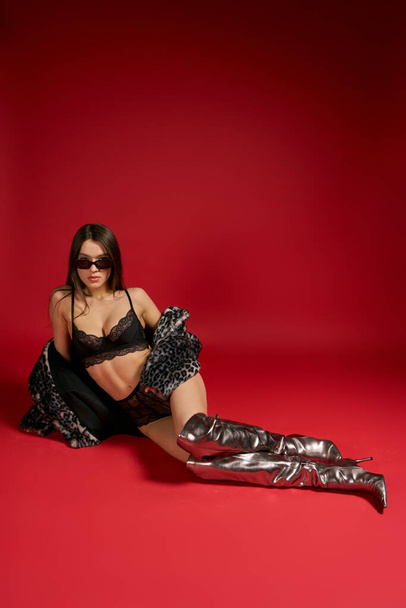 Woman in black and silver outfit sits gracefully on the floor with wet hair. - Foto, Bild