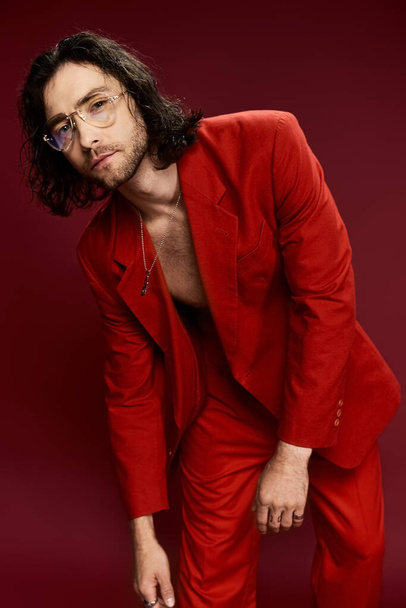 Un hombre guapo con un llamativo traje rojo y gafas posa con confianza, exudando estilo y sofisticación. - Foto, Imagen