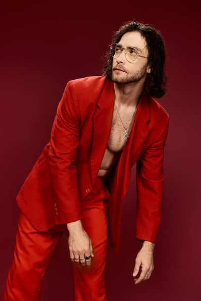 Красавчик в красном костюме, забавная поза без рубашки в студии.. - Фото, изображение