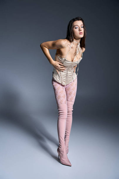 Young woman in pink tights and boots striking a stylish pose. - Foto, immagini