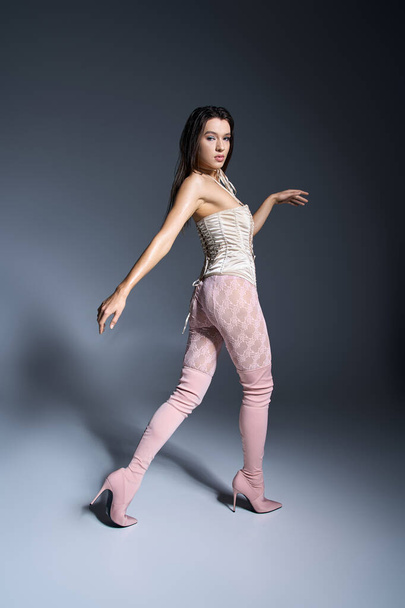 Young woman with wet hair in stylish attire of white corset and pink pants. - Photo, Image