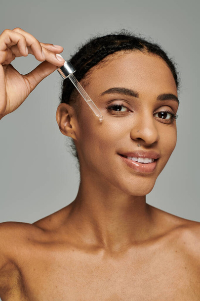 Young African American woman in strapless top applying serum - Photo, Image