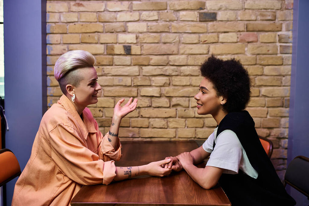Dos mujeres diversas conversando en una mesa de café. - Foto, Imagen