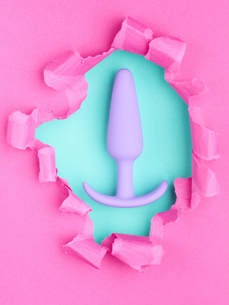 σεξ παιχνίδι πάνω από τρύπα σε ροζ χάρτινο φόντο - Φωτογραφία, εικόνα