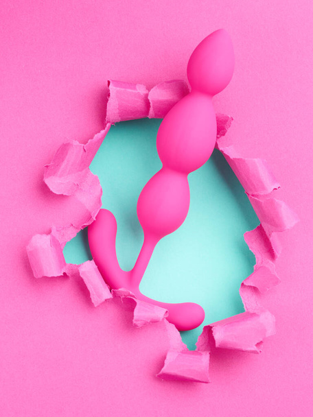 секс-іграшка над отвором у рожевому паперовому фоні - Фото, зображення