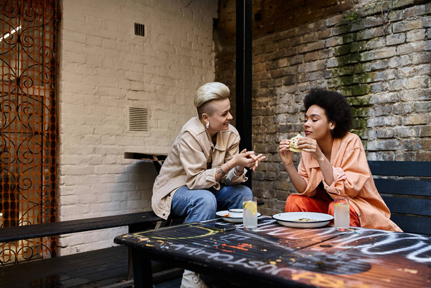 Diverse couple of lesbians enjoying food at a table. - Fotoğraf, Görsel