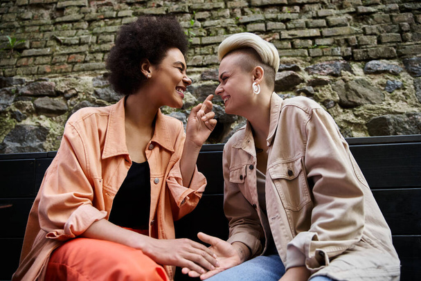 Monipuolinen pari tyylikkäitä lesboja jakaa hetken läheisyyttä viihtyisässä kahvilassa.. - Valokuva, kuva