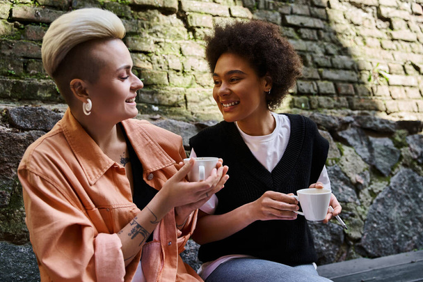 Two diverse women sitting closely, engaged in conversation in a cozy cafe setting. - Foto, Bild