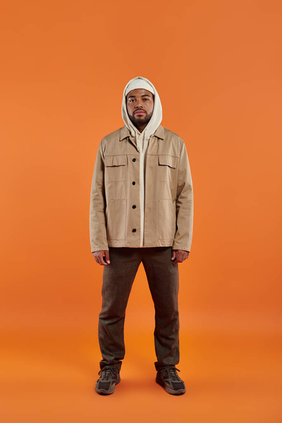 Stylish African American man posing on vibrant orange backdrop. - Photo, Image