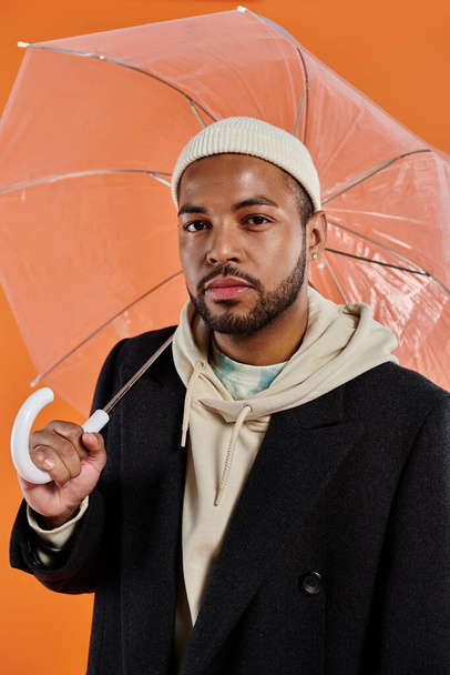 Afro-Amerikaanse man poseert stijlvol onder een paraplu. - Foto, afbeelding