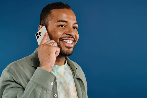Κομψό Αφρο-Αμερικανός άντρας μιλάει στο κινητό του σε ένα ζωντανό φόντο. - Φωτογραφία, εικόνα