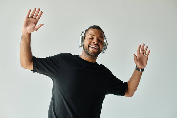 Hombre afroamericano con camisa negra escuchando auriculares. - Foto, imagen