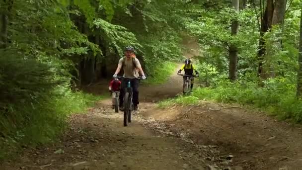 Three cyclists men riding electric bikes outdoors. Male tourists biking in the mountains, wearing helmets and backpacks. Concept of sport, active leisure and nature. - Video