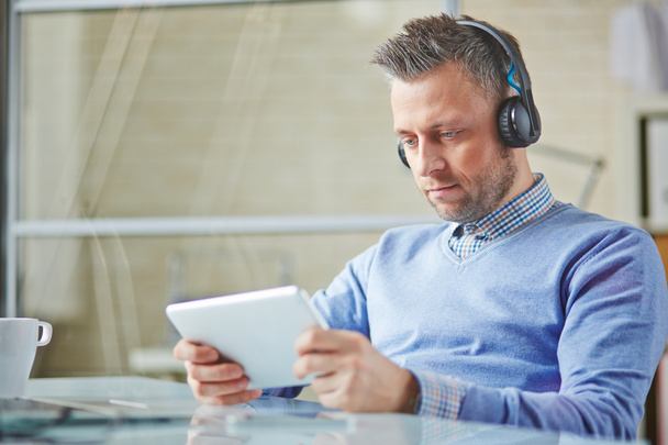 Businessman with earphones and touchpad - Foto, Bild