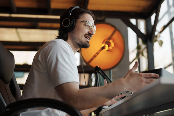 Man wearing headphones recording a podcast episode in a modern studio setup, discussing topics with enthusiasm and engagement. - Foto, Imagem