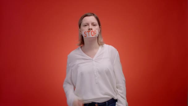 A woman with a closed mouth with tape, backing tape away screams. Stop being silent while youve been abused by someone, cry to get help. High quality 4k footage - Materiał filmowy, wideo