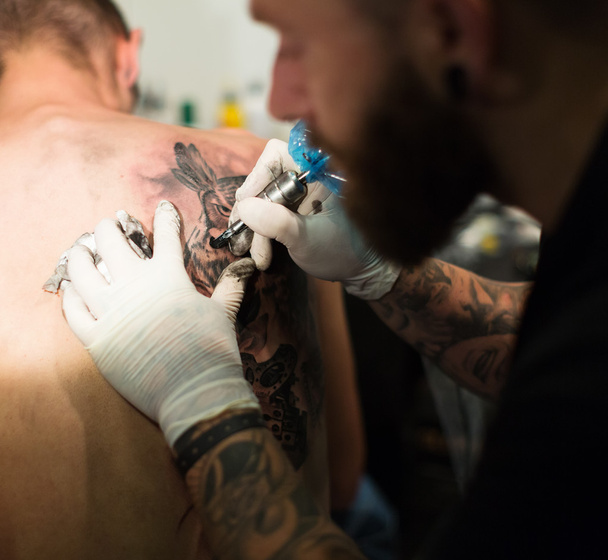 Artist doing  tattoo on client - Foto, afbeelding