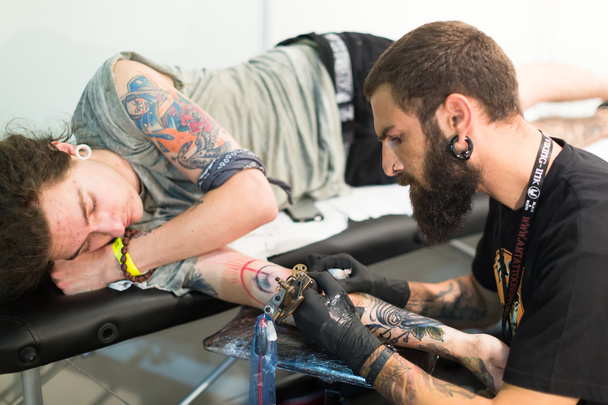 Artist doing  tattoo on client - Zdjęcie, obraz