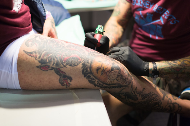 Artist doing tattoo on  client's leg - Zdjęcie, obraz