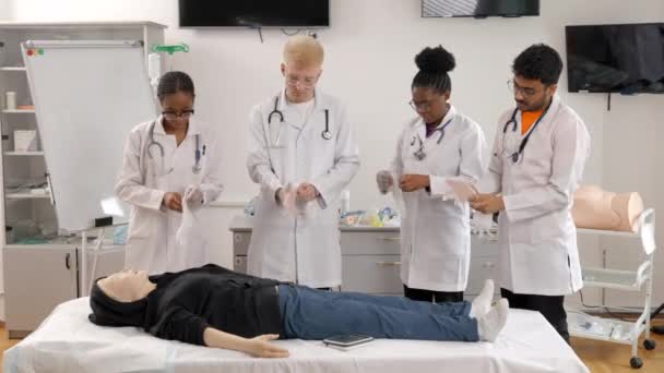Arztgruppe steht mit Schaufensterpuppe am Bett bei Erste-Hilfe-Kurs - Filmmaterial, Video