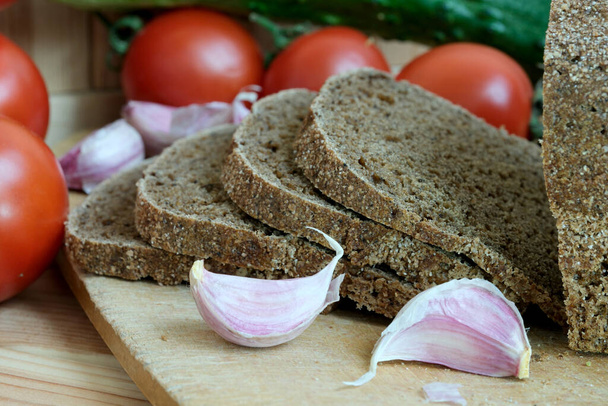 Taze dilimlenmiş ekmek ve sarımsaklı karanfille kaplı bir kesim tahtası.. - Fotoğraf, Görsel