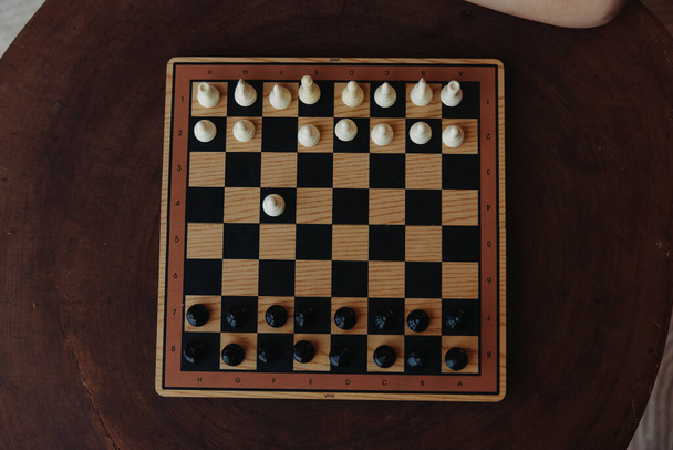 A következő lépésüket tervező személy sakkozni fog a fa asztalon, fekete-fehér darabokkal - Fotó, kép