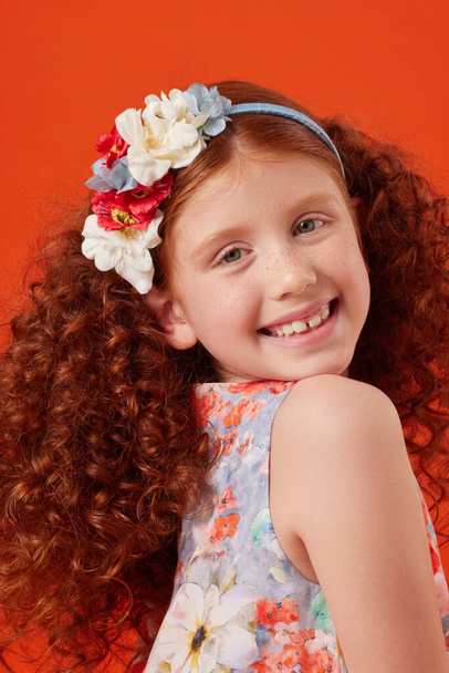 Smiling Redhead Girl with Freckles in Blue Floral Dress on Orange Background - Foto, imagen