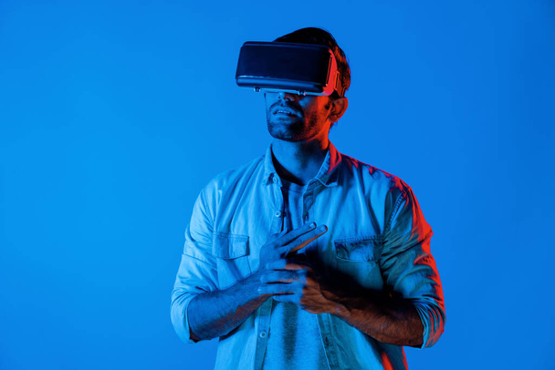 Uomo intelligente caucasico con vetro VR e pistola a mano in mano. Gamer utilizza le cuffie future per la realtà virtuale digitale o l'innovazione futuristica per entrare nel meta mondo o giocare al gioco d'azione. Deviazione. - Foto, immagini