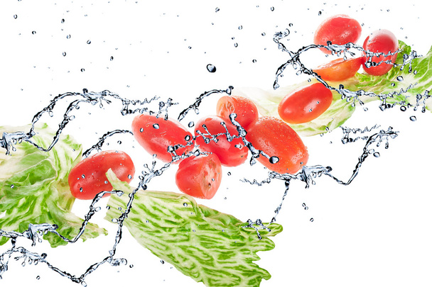 Salat mit Tomaten auf weißem Hintergrund und Spritzwasser - Foto, Bild