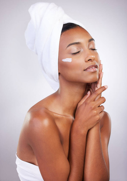 Skincare, model and cream for beauty, dermatology and routine facial treatment. Spa, wellness and skin glow aesthetic on white studio background with black woman, cosmetics and luxury collagen shine. - 写真・画像