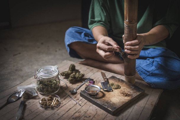 A man prepares marijuana on a cutting board to smoke, person who smokes drugs, drug addict, Drugs addiction and withdrawal symptoms concept. drugsInternational Day against Drug Abuse. - Fotoğraf, Görsel