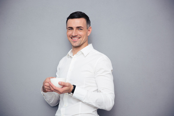 Cheerful young businessman holding cup of coffee - Foto, Imagen