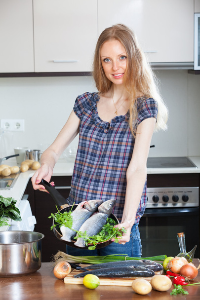 blonde woman cooking lubina fish - Foto, Imagen