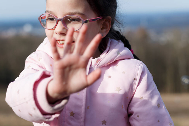Menina sorridente em óculos brincando com bolhas de sabão em um parque sem neve de inverno - Foto, Imagem